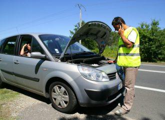Homme en gilet de sécurité près d'une voiture en panne